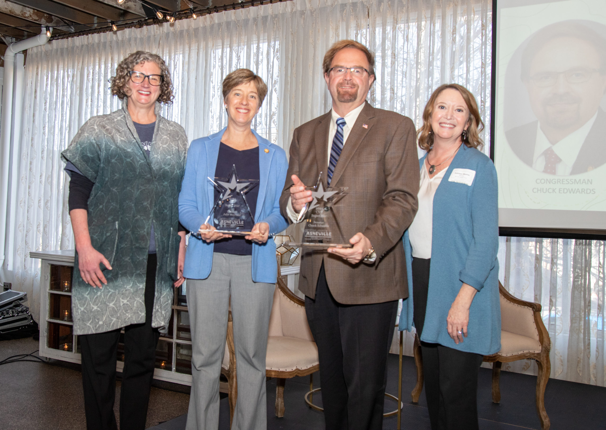 President & CEO of Explore Asheville Vic Isley (far left) and Buncombe County Tourism Development Authority Board Chair Kathleen Mosher (far right) recognized state lawmakers Congressman Chuck Edwards, Senator Julie Mayfield, and Senator Warren Daniel (not pictured) with Asheville Superstar Awards for their outstanding contributions